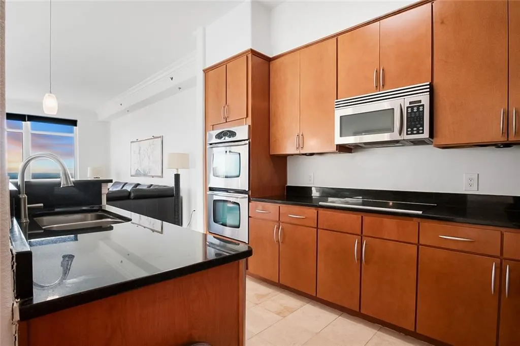 Kitchen featuring pendant lighting, a sink, stainless steel appliances, and brown cabinetry