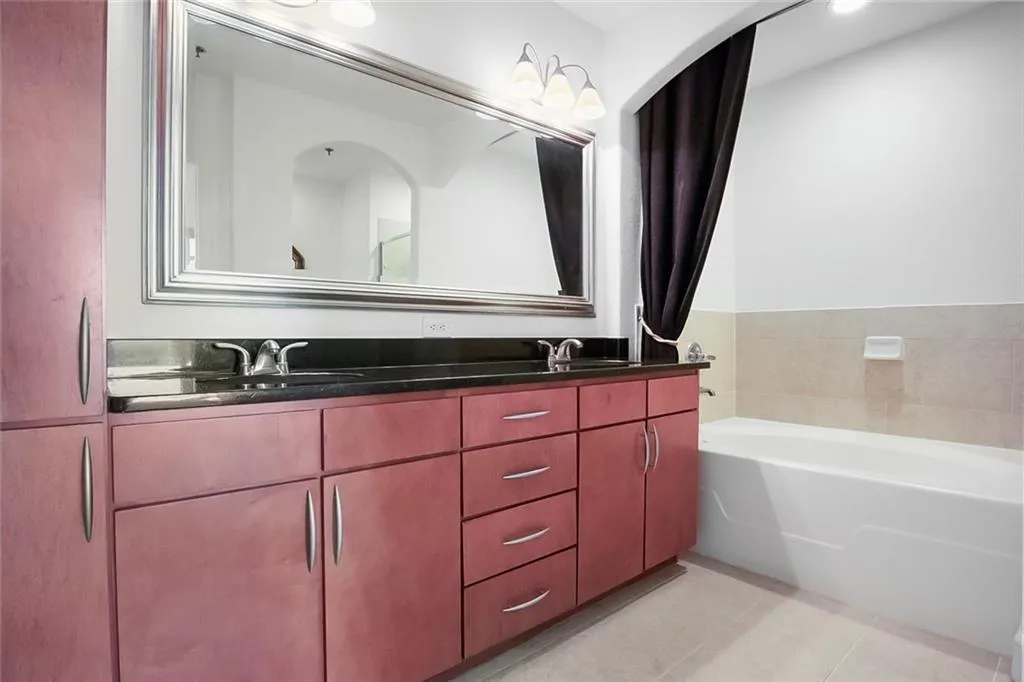 Full bath featuring double vanity, a bath, tile patterned flooring, and a sink
