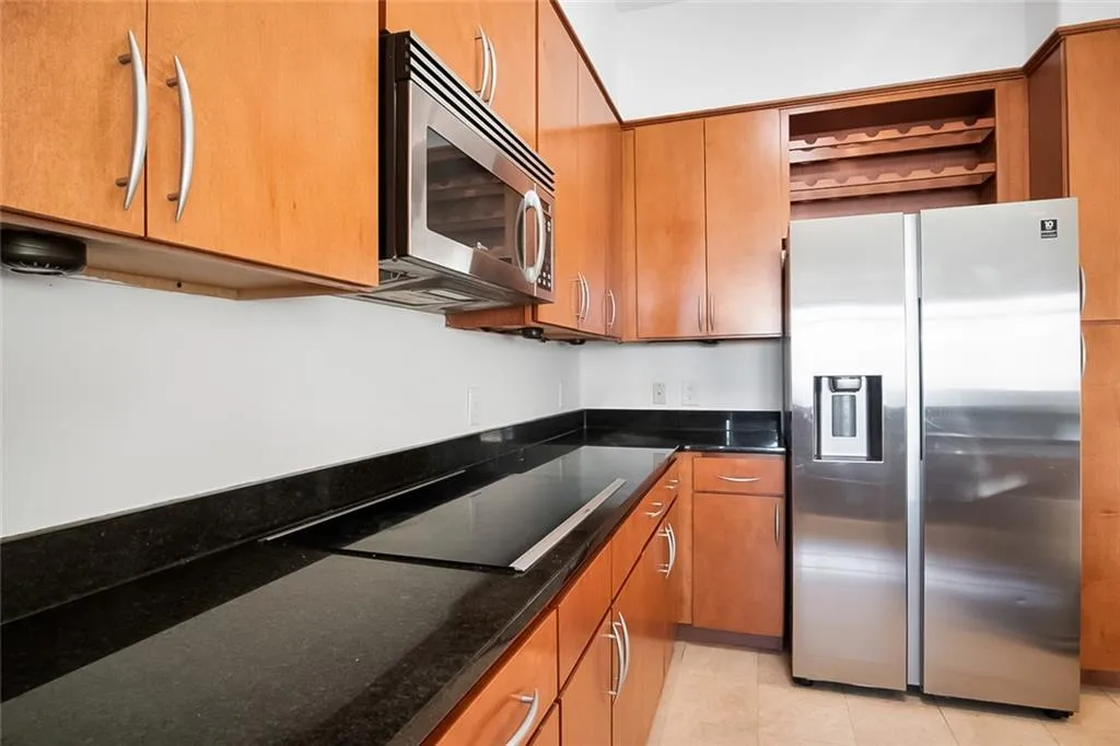 Kitchen featuring open shelves, brown cabinetry, light tile patterned floors, and appliances with stainless steel finishes