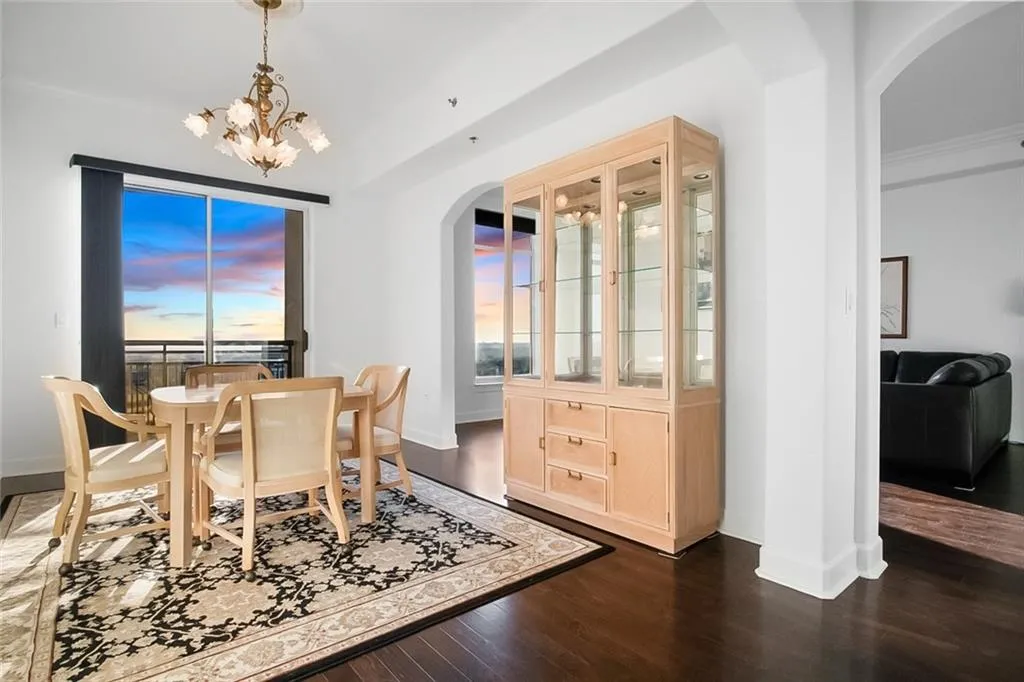 Dining area featuring arched walkways, dark wood-style flooring, baseboards, and a chandelier