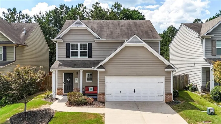 Two-story residence featuring a covered front porch, attached garage, and brick accents