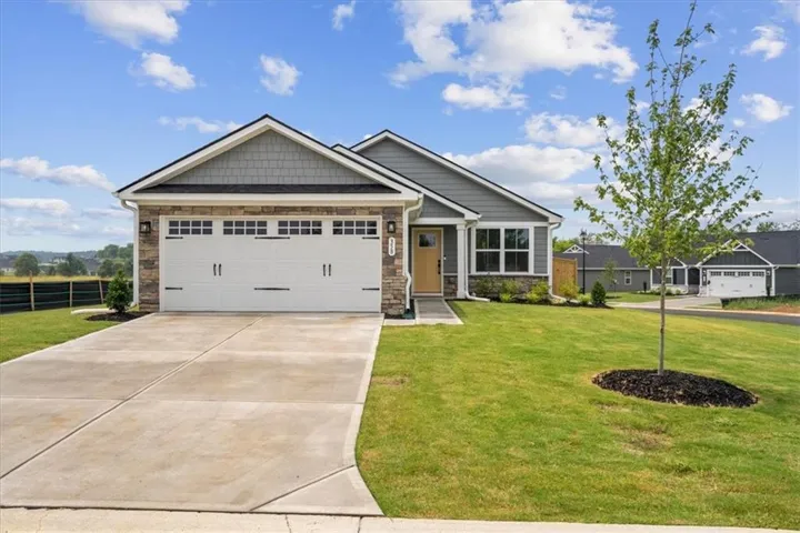 Contemporary ranch-style exterior featuring a stone and siding facade, an attached two-car garage with decorative hardware, a covered front entry, and a concrete driveway