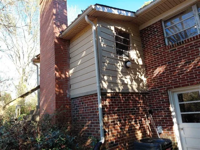 View of side of home featuring a chimney and brick siding