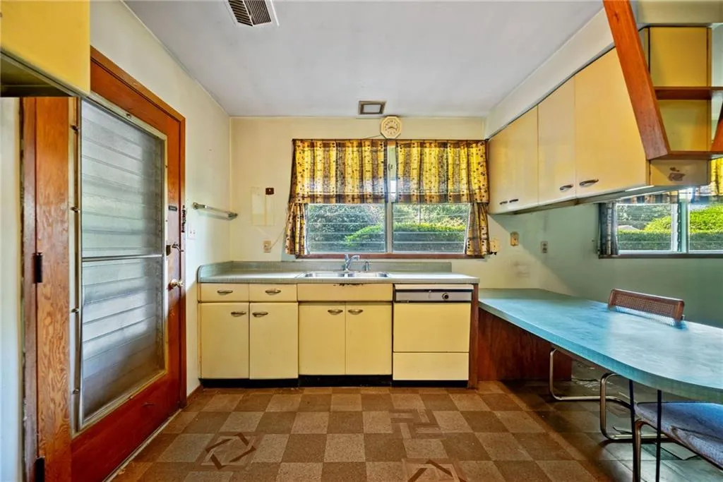 Kitchen with dark flooring, white dishwasher, cream cabinets, and light countertops