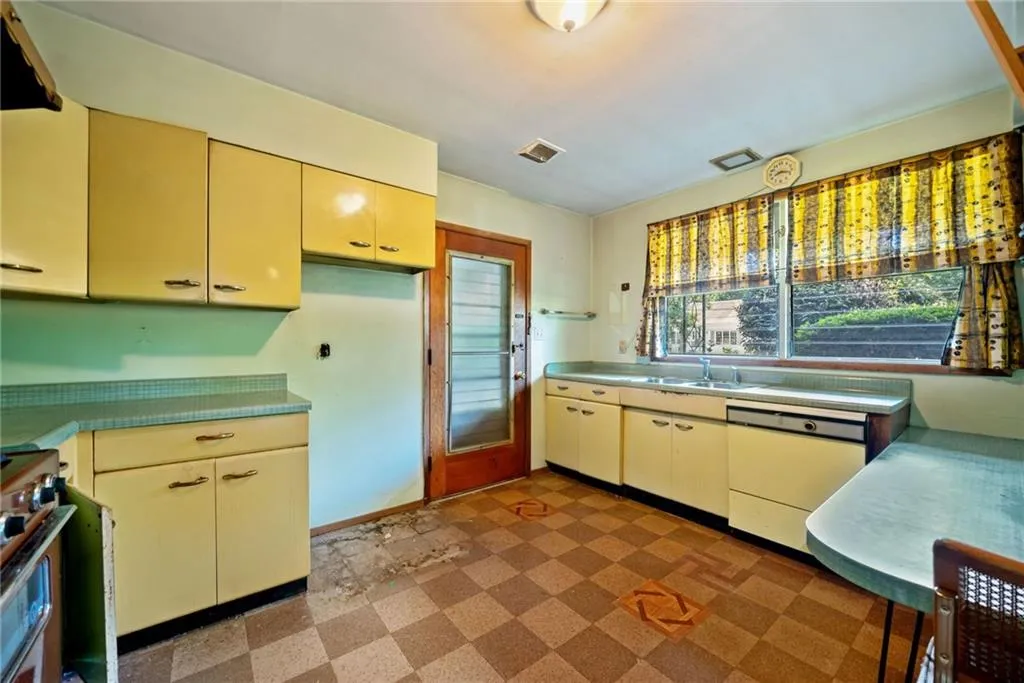 Kitchen featuring cream cabinets, tile patterned floors, stainless steel stove, and white dishwasher