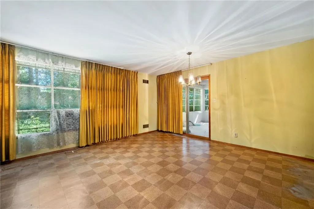 Unfurnished room featuring light flooring and a chandelier