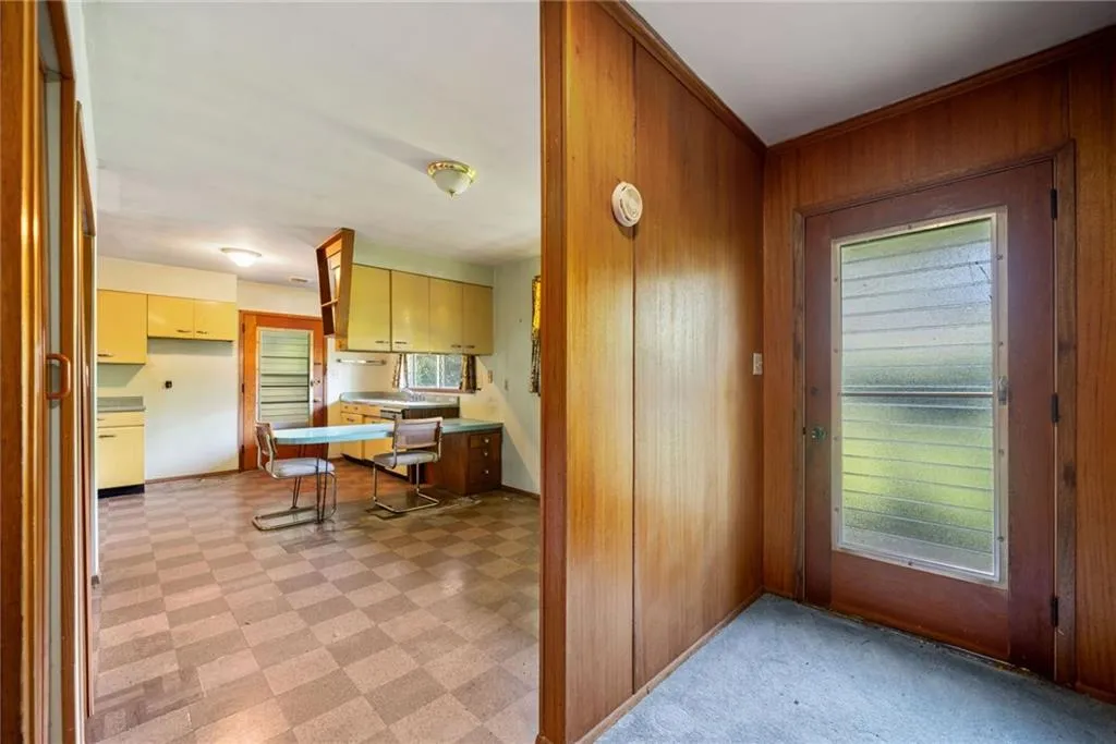 Kitchen featuring wooden walls, light flooring, and cream cabinetry