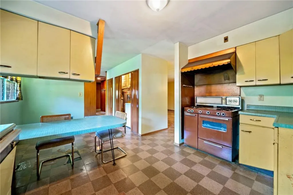 Kitchen featuring cream cabinetry, gas stove, wall chimney exhaust hood, and yellow cabinetry
