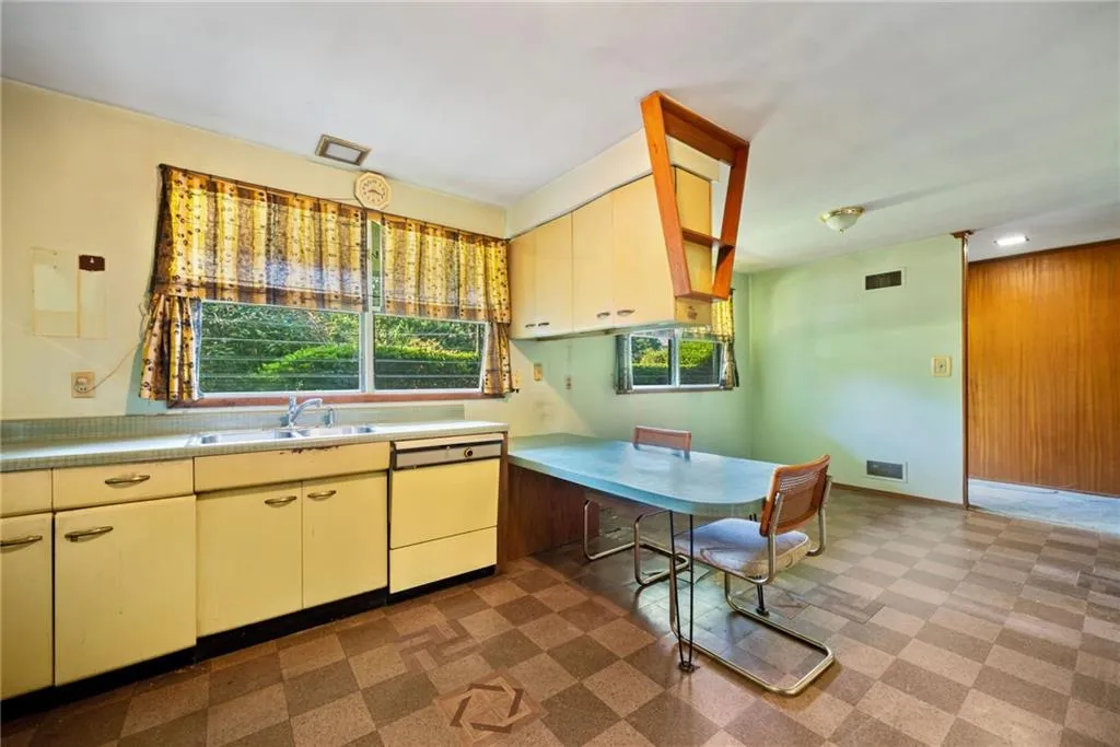 Kitchen with tile patterned floors, dishwasher, cream cabinets, and light countertops