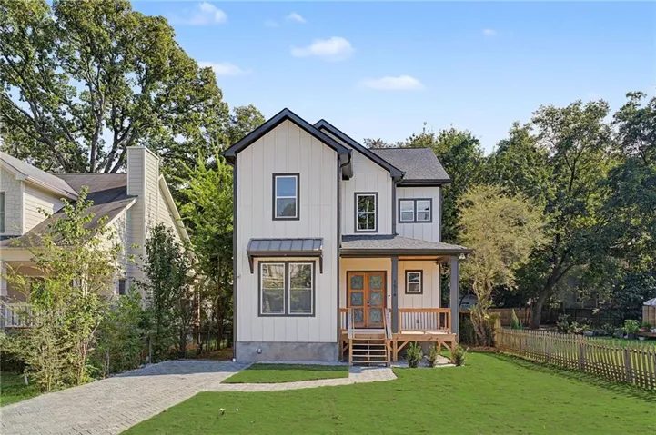 Modern farmhouse exterior with vertical white siding, black-framed windows, a covered front porch, and a wood entry door