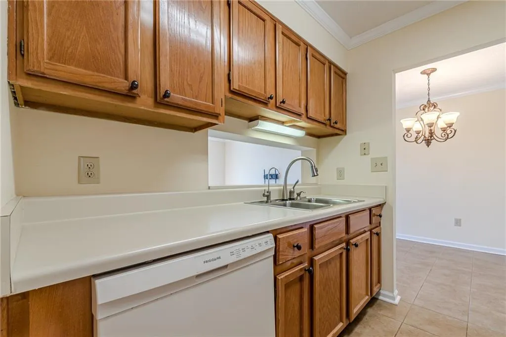 Kitchen featuring hanging light fixtures, a chandelier, dishwasher, crown molding, and sink
