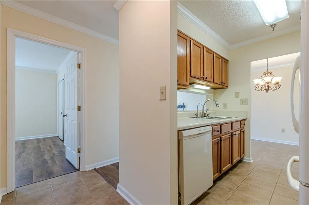 Kitchen featuring white appliances, ornamental molding, sink, and hanging light fixtures