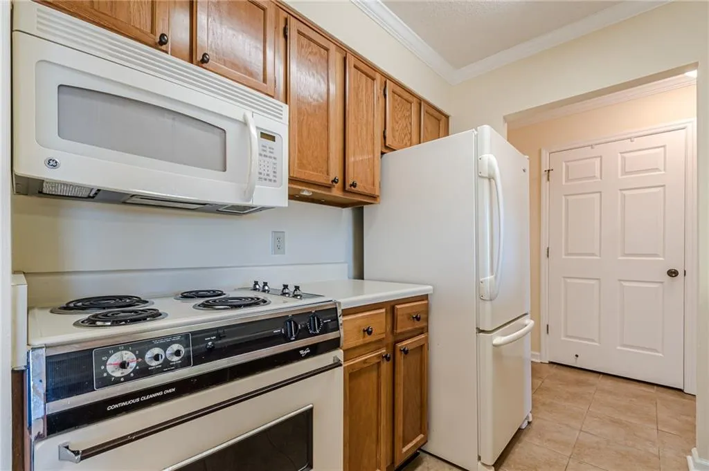 Kitchen featuring ornamental molding, light tile patterned floors, and white appliances