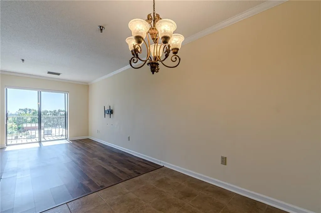 Spare room featuring an inviting chandelier, crown molding, a textured ceiling, and dark wood-type flooring