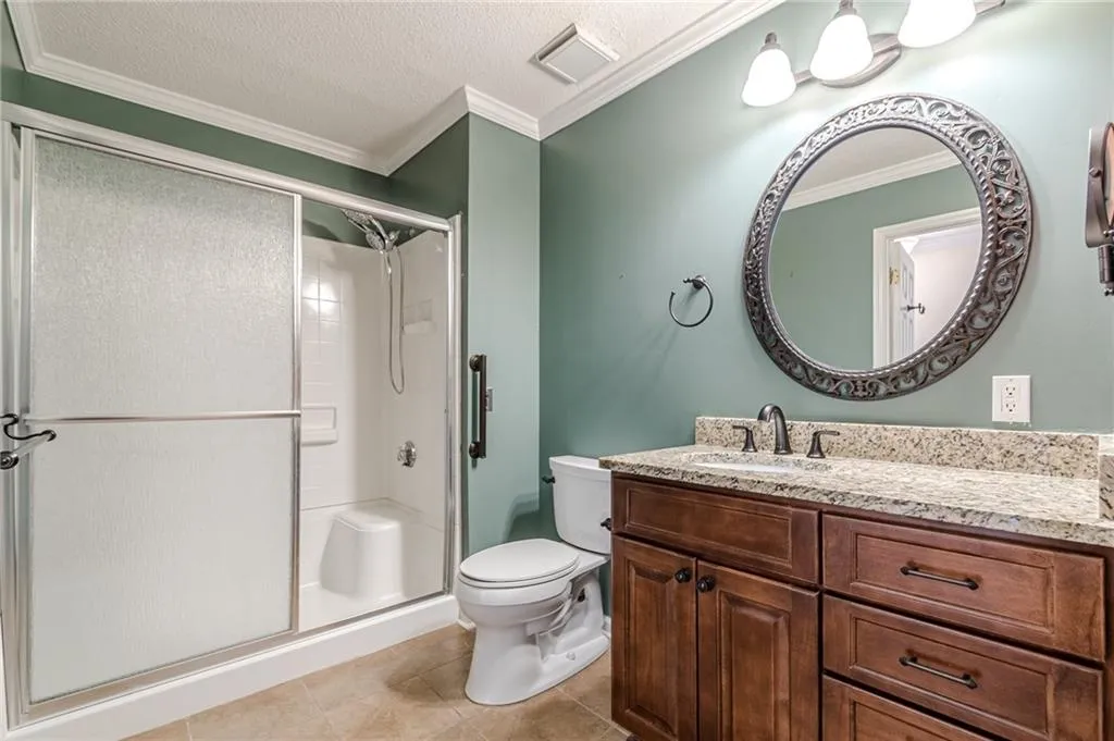 Bathroom featuring vanity, toilet, ornamental molding, and a shower with shower door