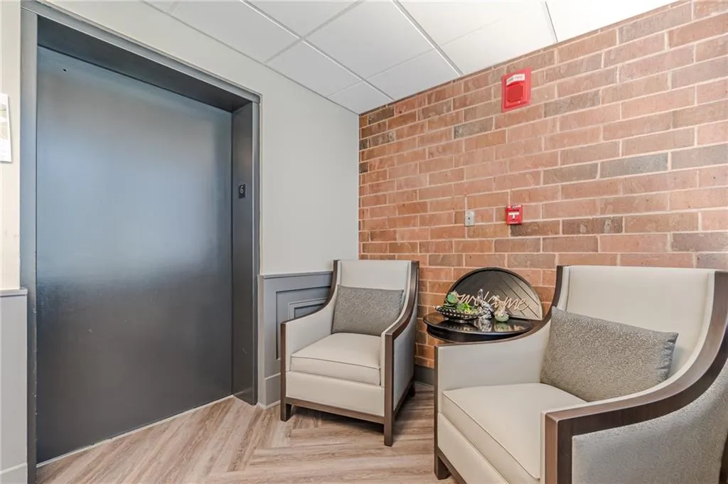 Living area with light parquet flooring, brick wall, and elevator