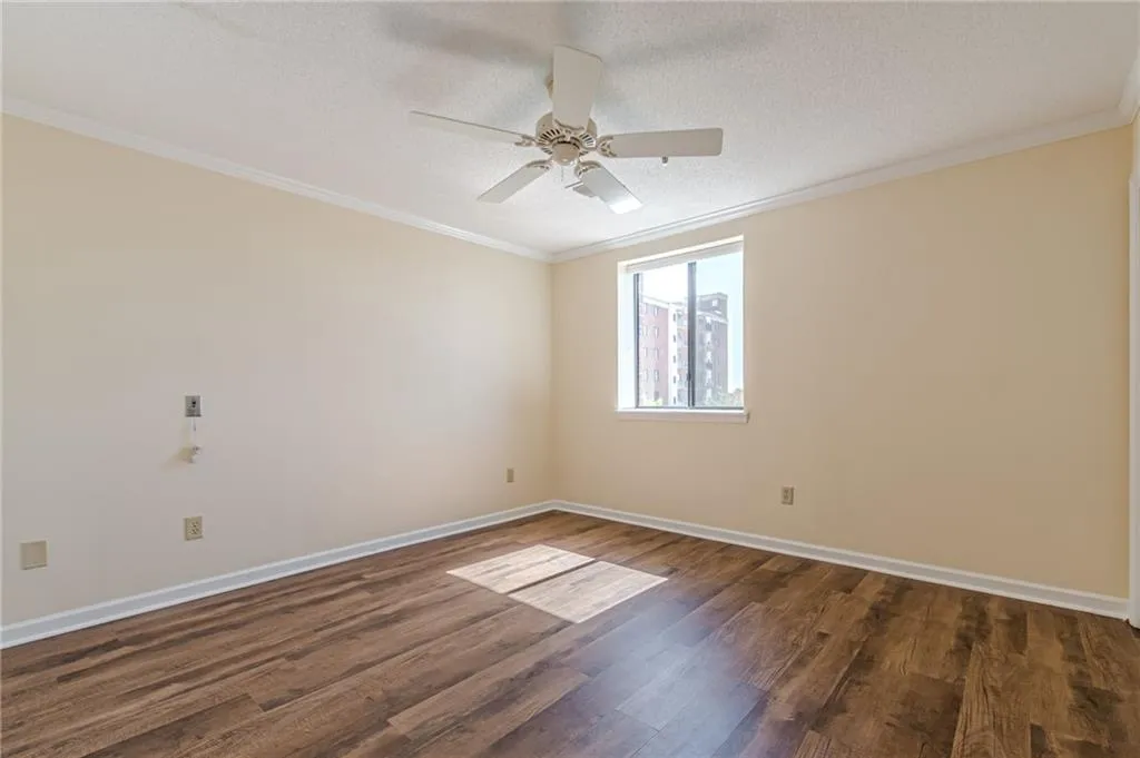 Unfurnished room featuring dark wood-type flooring, crown molding, and a textured ceiling