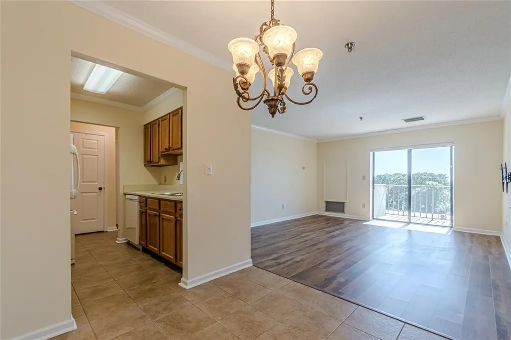 Kitchen featuring white dishwasher, sink, crown molding, decorative light fixtures, and light hardwood / wood-style floors
