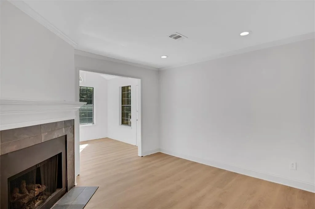 Unfurnished living room featuring light wood-type flooring and ornamental molding