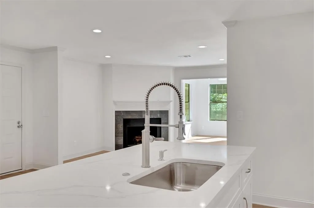 Kitchen featuring hardwood / wood-style flooring, a fireplace, sink, and light stone countertops