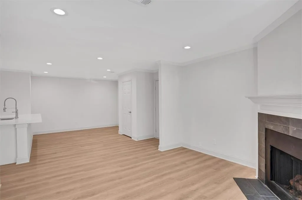 Living room featuring ornamental molding, a tiled fireplace, sink, and light hardwood / wood-style floors