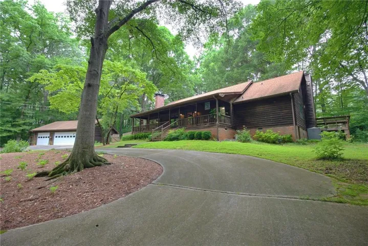 Wood-sided home with a covered front porch and a red asphalt shingle roof