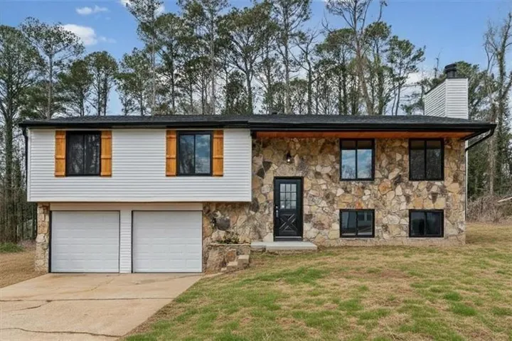 Split-level home featuring a stone facade and white siding
