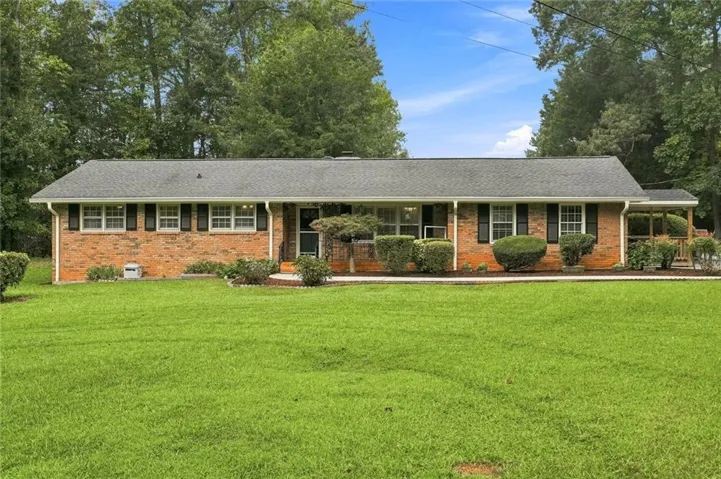 Brick exterior with a gray shingle roof, black window shutters, and a covered porch