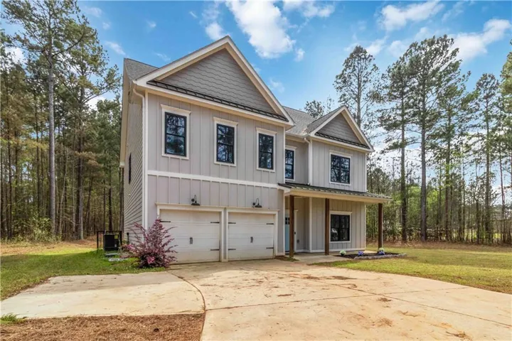 Modern inspired farmhouse featuring board and batten siding, a front yard, an attached garage, and a shingled roof