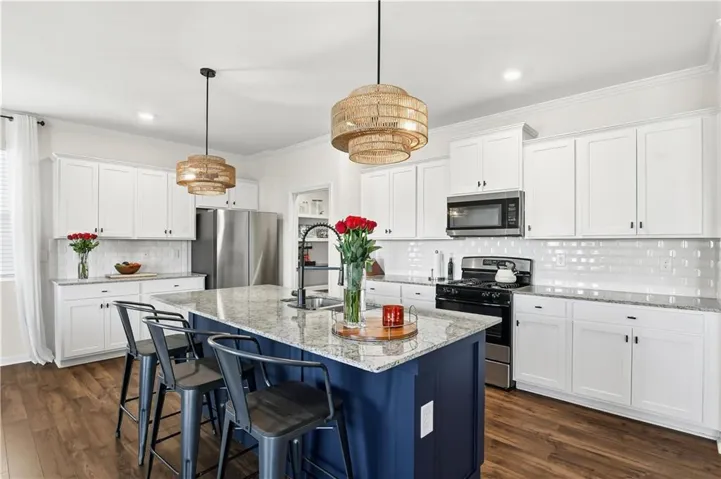 Kitchen featuring a central island with a contrasting blue base, light-toned countertop, and integrated sink