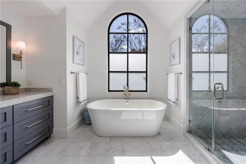Bathroom with vanity, plus walk in shower, marble floors, vaulted ceiling and chandelier