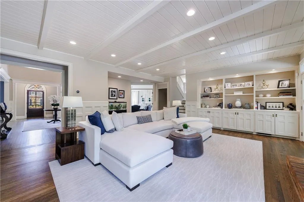 Family room with built in shelves, hardwood flooring, and beamed ceiling