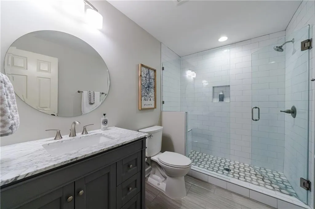 Bathroom featuring toilet, large vanity, tile floors, and a shower with shower door