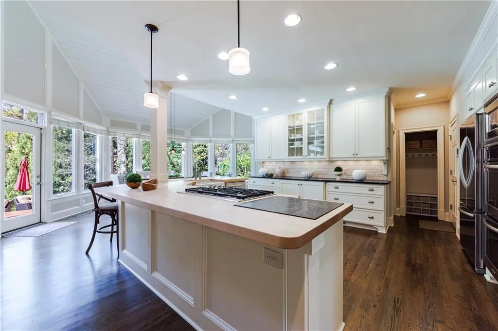 Kitchen featuring white cabinets, tasteful backsplash, hardwood-flooring, and pendant lighting
