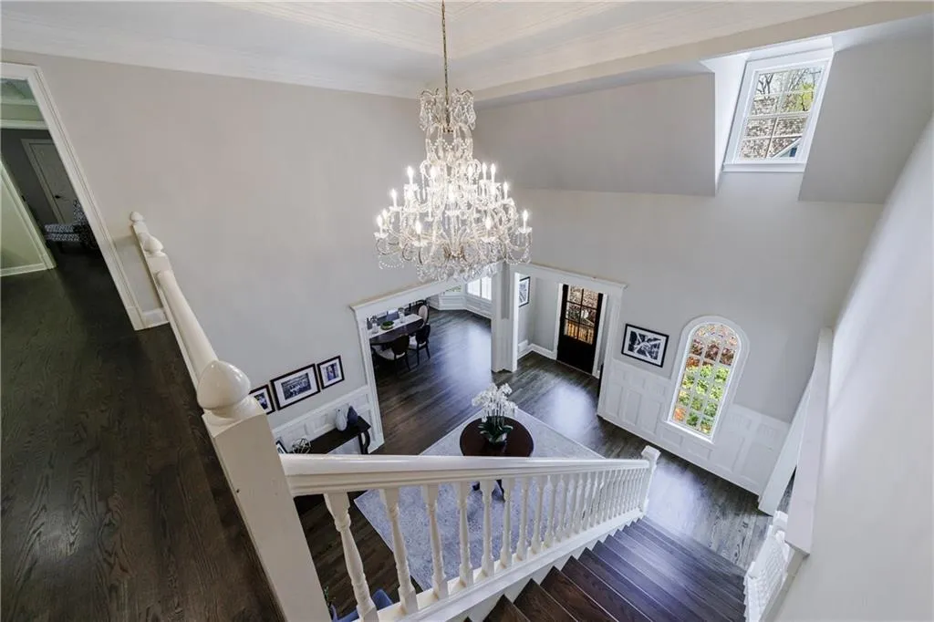 Stairway featuring a chandelier, ornamental molding, hardwood flooring, and a wealth of natural light
