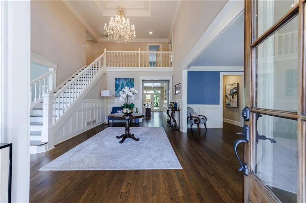 Entryway featuring dark hardwood floors, a notable chandelier, a raised ceiling, crown molding, and french doors