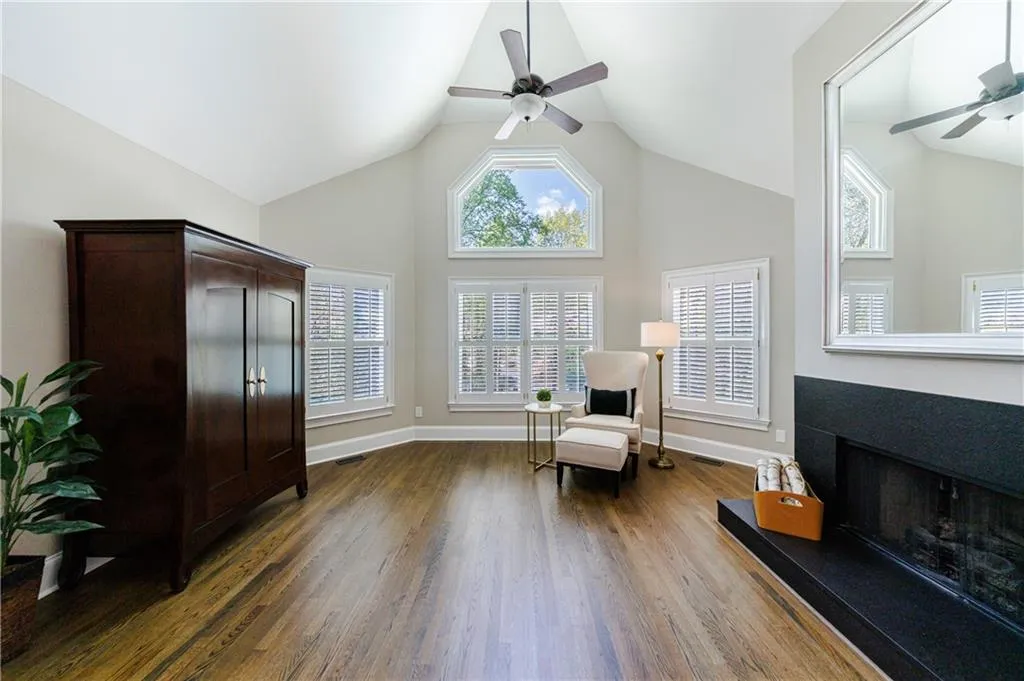 Sitting room with high vaulted ceiling, bay windows, hardwood flooring, fireplace and ceiling fan