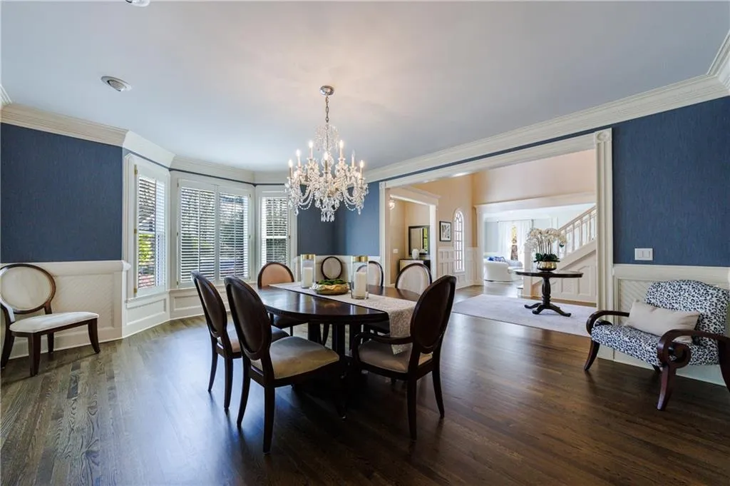 Dining space with crown molding, dark wood flooring, and an inviting chandelier
