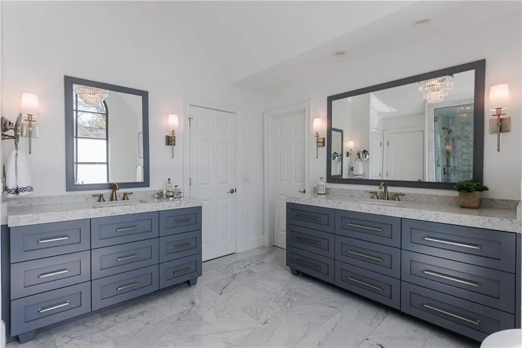 Bathroom with a notable chandelier, marble flooring, custom double vanity, and walk in shower