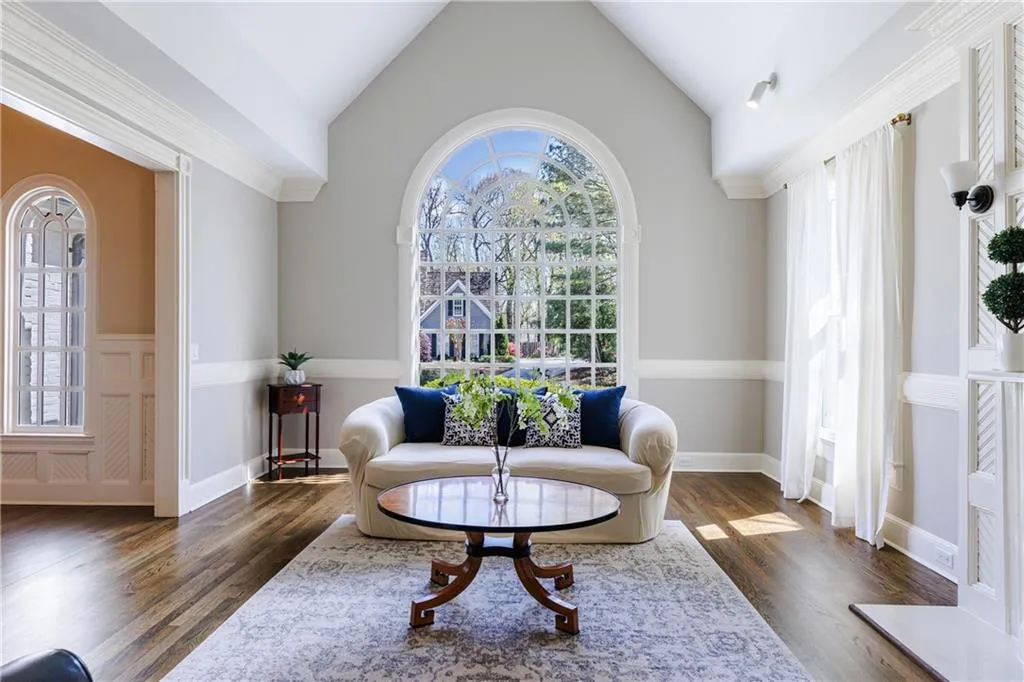 Living room with a wealth of natural light, dark wood flooring, and vaulted ceiling