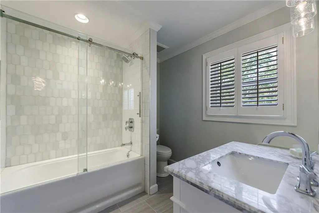 Full bathroom with toilet, tiled shower / bath, combo, vanity, crown molding, and tile floors, large walk-in closet