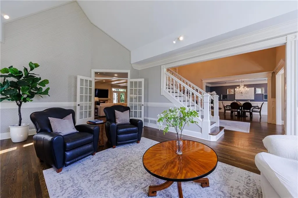 Living room featuring french doors, a chandelier, dark wood flooring, and high vaulted ceiling