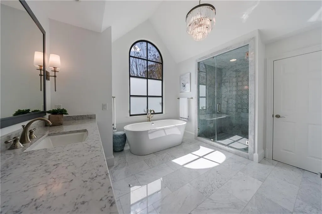 Bathroom featuring shower with separate bathtub, vanity, marble floors, a notable chandelier, and lofted ceiling