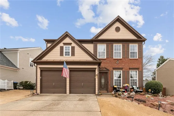Traditional-style house featuring driveway, a garage, and brick siding