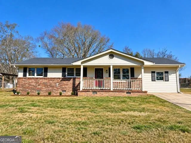 Ranch-style residence featuring a brick and siding exterior, a covered front porch with white railing, and a dark shingle roof