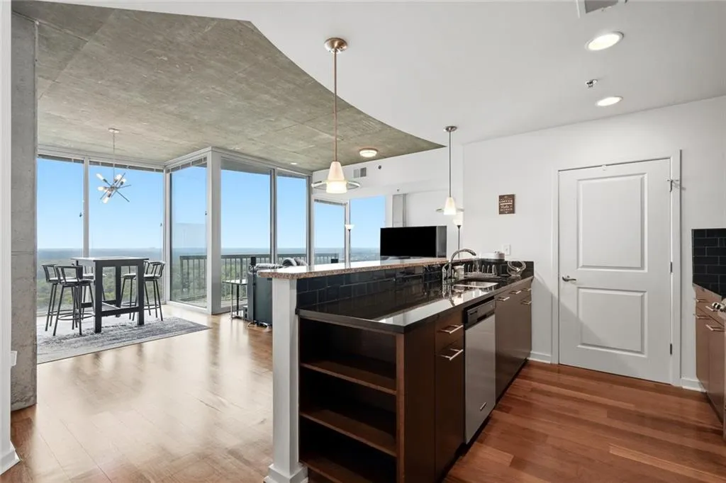 Contemporary kitchen featuring a dark countertop island with a built-in sink and stainless steel dishwasher