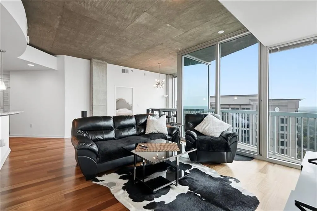 Spacious interior featuring wood-finish flooring, floor-to-ceiling windows, and a concrete ceiling with integrated lighting