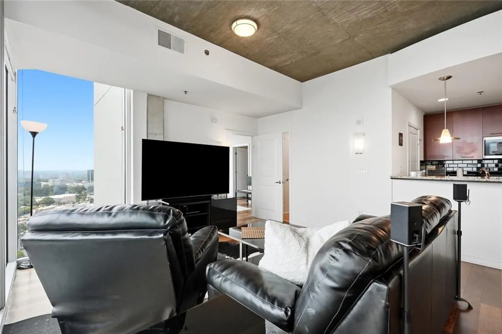 Open-concept living space featuring expansive windows, a concrete ceiling, and wood-finish flooring