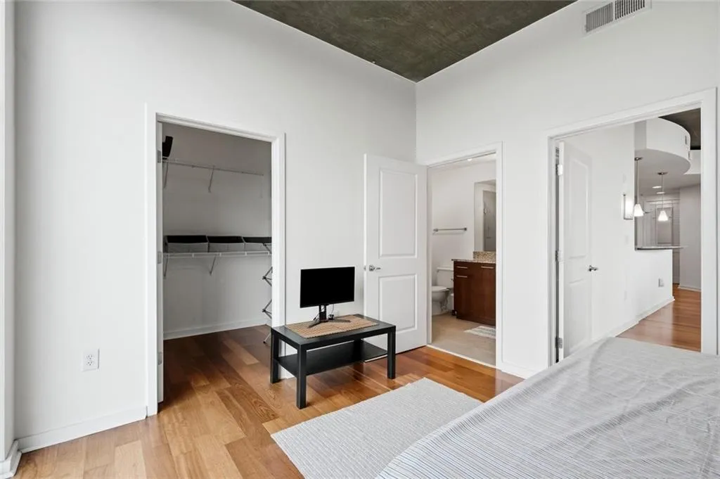 Bedroom featuring light wood-finish flooring, high ceilings with exposed concrete, and bright white walls