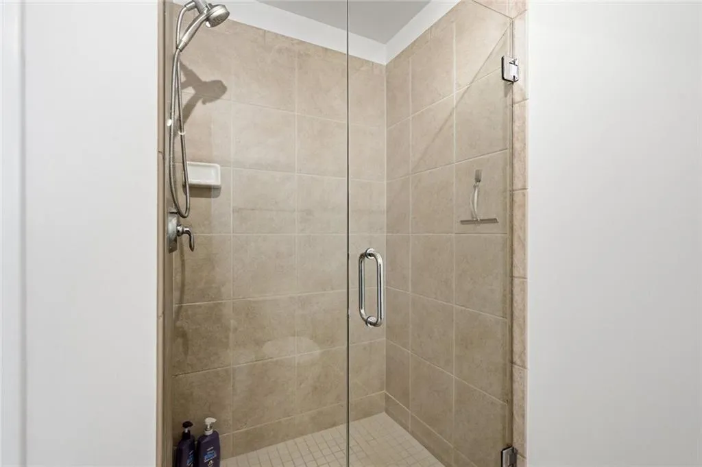 Glass-enclosed shower featuring large format wall tiling and a mosaic tile floor